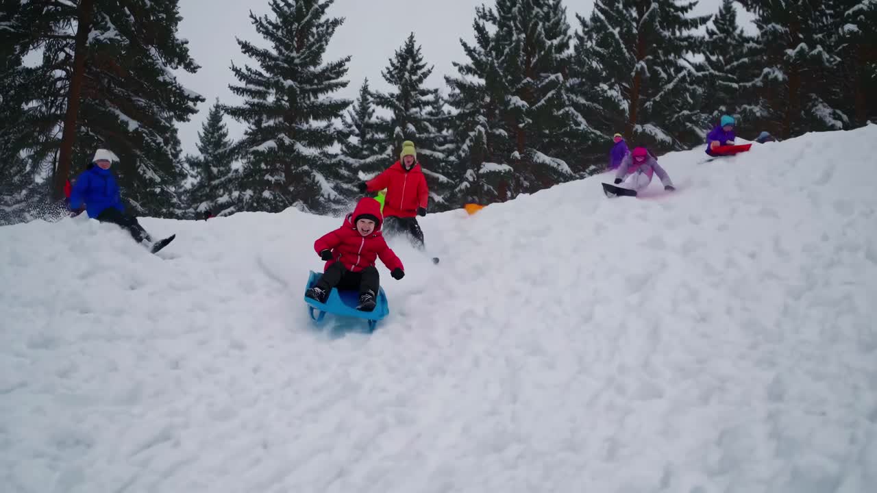 A dynamic video captures children sledding down a snowy hill. Shot from a low angle, it highlights