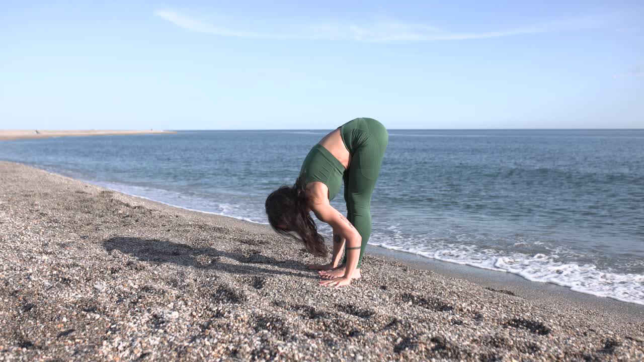Young woman performing uttanasana pose on the beach
