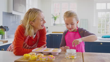 Großmutter-Und-Enkelin-Haben-Spaß-Daran,-Hausgemachte-Kuchen-Auf-Der-Küchentheke-Zu-Hause-Zu-Dekorieren