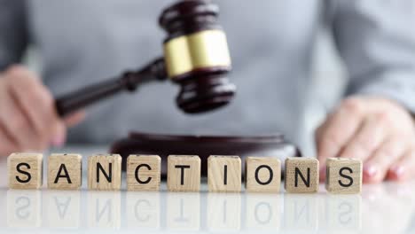Hammer and words sanction are written in letters on table
