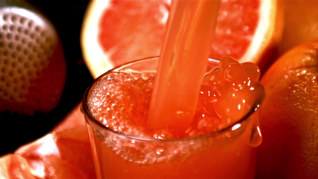 Succo di pompelmo fresco che si versa in un bicchiere al rallentatore