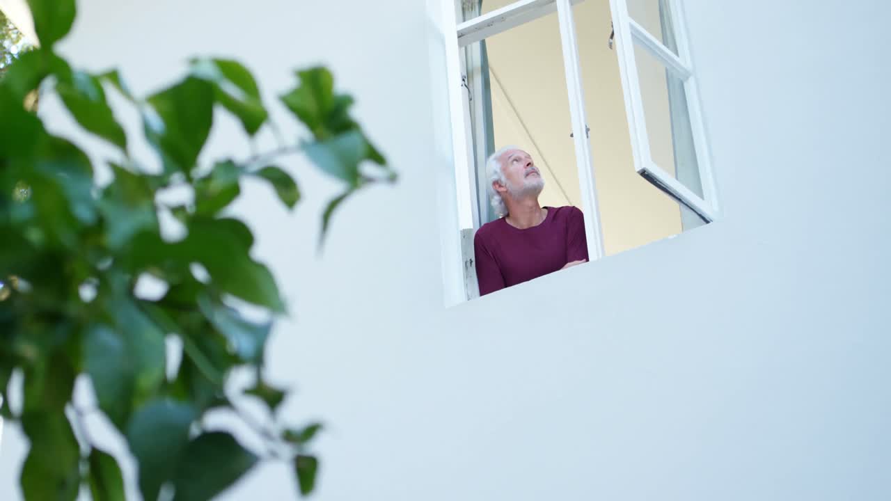 hombre mayor mirando por la ventana en casa 4k