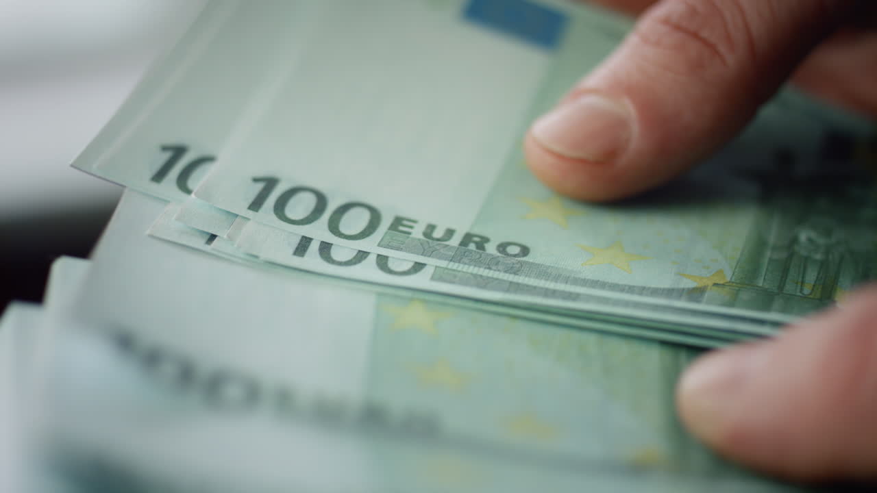 Nærbillede af hænder, der tæller kontanter. En kasserer holder sedler i europæisk valuta.