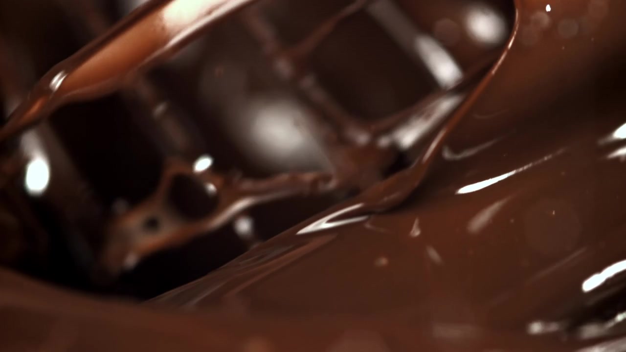 Cioccolato fuso denso che turbina e cola al rallentatore