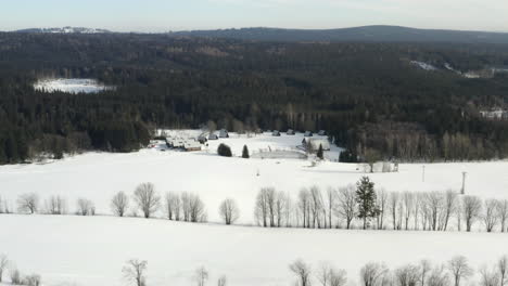 Toma-Aérea-Del-Campamento-De-Invierno-Con-Cabañas-En-El-Paisaje-Montañoso-De-Invierno,-Destino-De-La-República-Checa