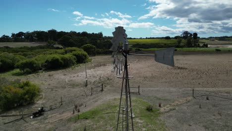 Aerial-orbiting-shot-of-Spinning-windmill-at-countryside-farm-of-Margaret-River-Region-in-summer,-Western-Australia