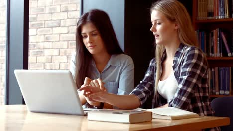 two students working on a laptop