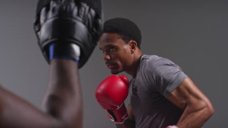 Close-Up-Shot-Of-Male-Boxer-Sparring-Working-Out-With-Trainer-Wearing-Punch-Mitts-Or-Gloves-Practising-For-Fight-1