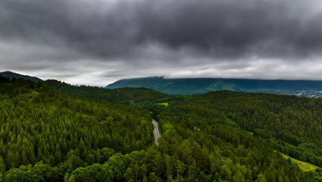 Hyperlapse-Aus-Der-Luft-über-Der-Autobahn,-Die-Durch-Grünen-Wald-Führt,-Stimmungsvolle-Wolken