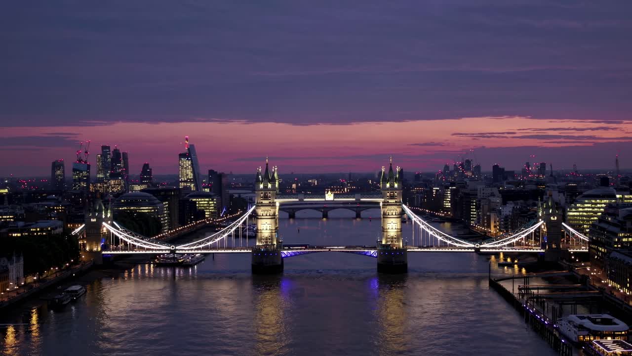 Aerial video captures London's Tower Bridge at dusk, with city lights reflecting on the Thames
