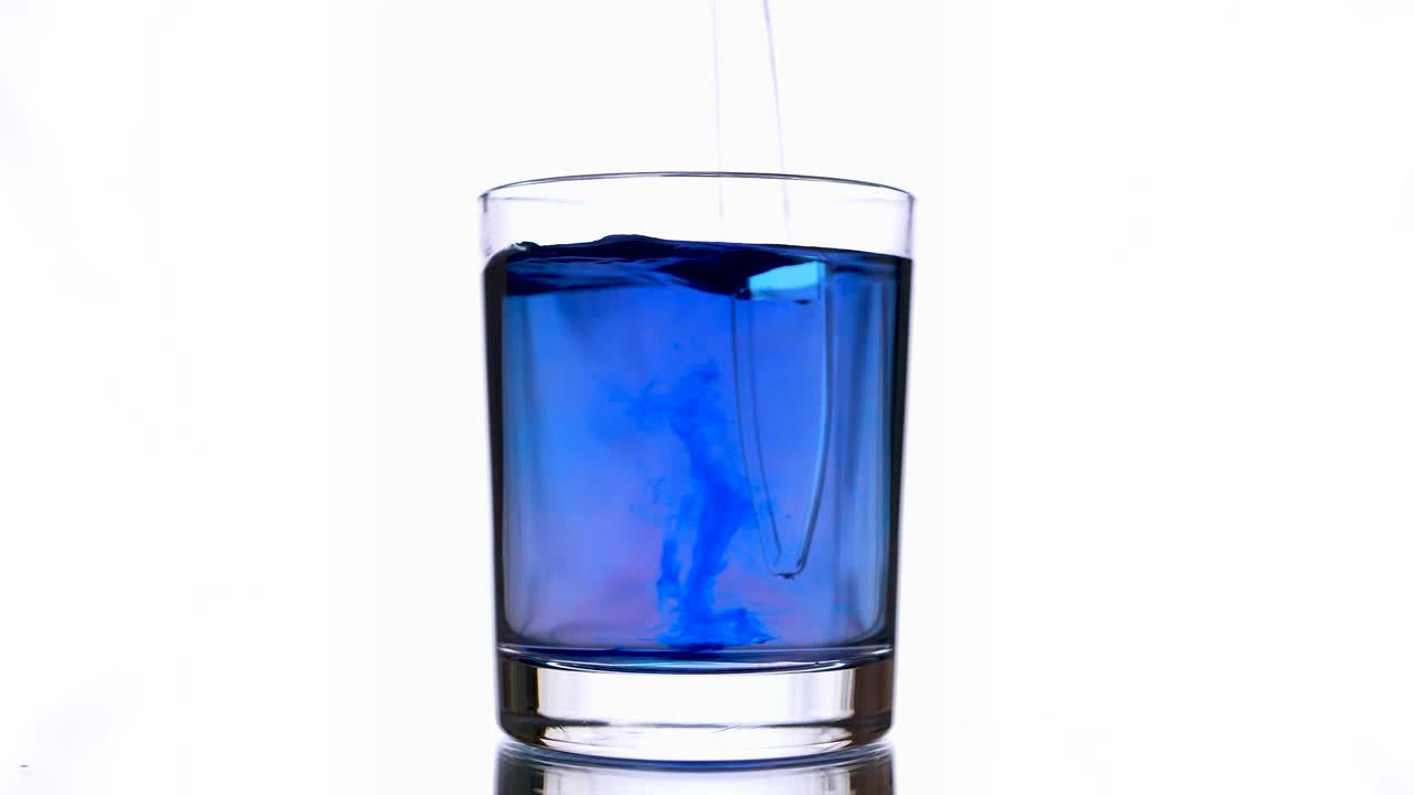 이 사진은 잉크 방울이 보라색 물 한 잔에 어지는 것을 보여줍니다.