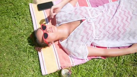 relaxing by pool, woman in red sunglasses sunbathing on colorful towel