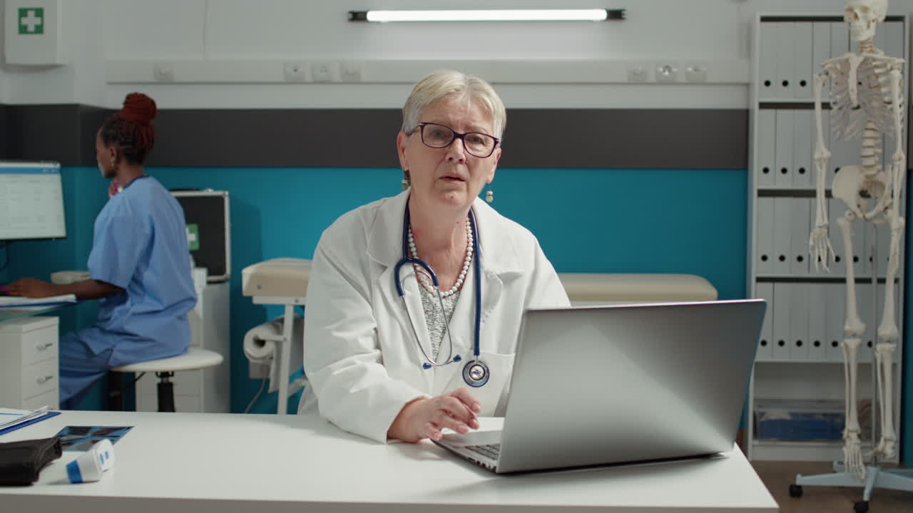 Portræt af praktiserende læge, der bruger bærbar computer ved helbredstjek