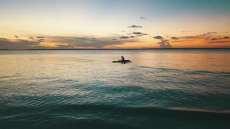 Calmer-slow-motion-aerial-flight-fly-backwards-drone-shot-at-sunset-over-surver-stand-up-board