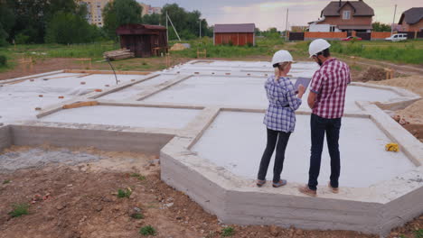 dos constructores: un hombre y una mujer están en la base del futuro edificio discutiendo el plan de trabajo