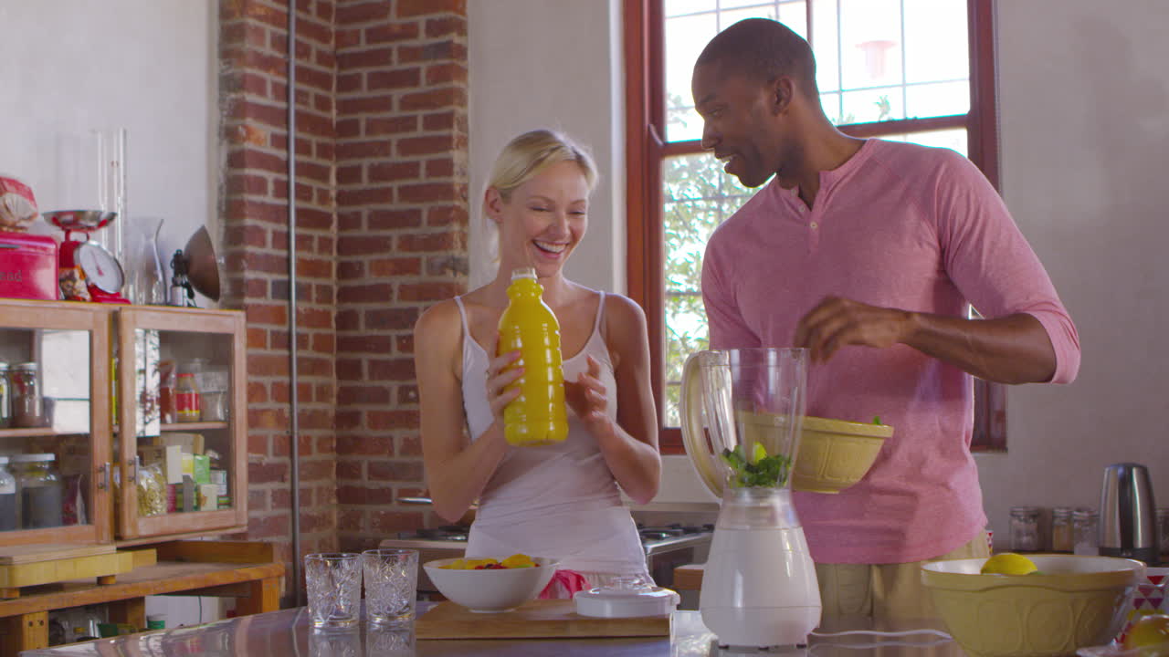 Couple métis préparant des smoothies ensemble à la maison, filmé avec une caméra R3D