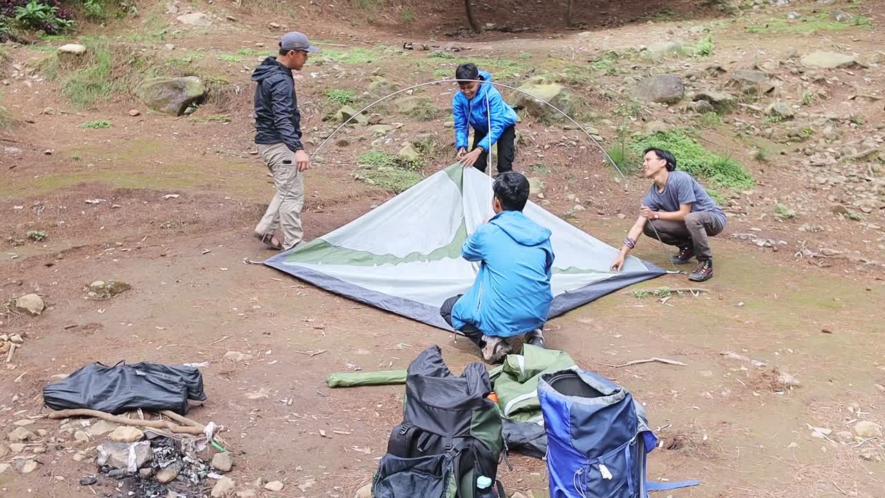 Kampçılar, toprak zeminde çadır kurmak için birlikte çalışıyorlar.
