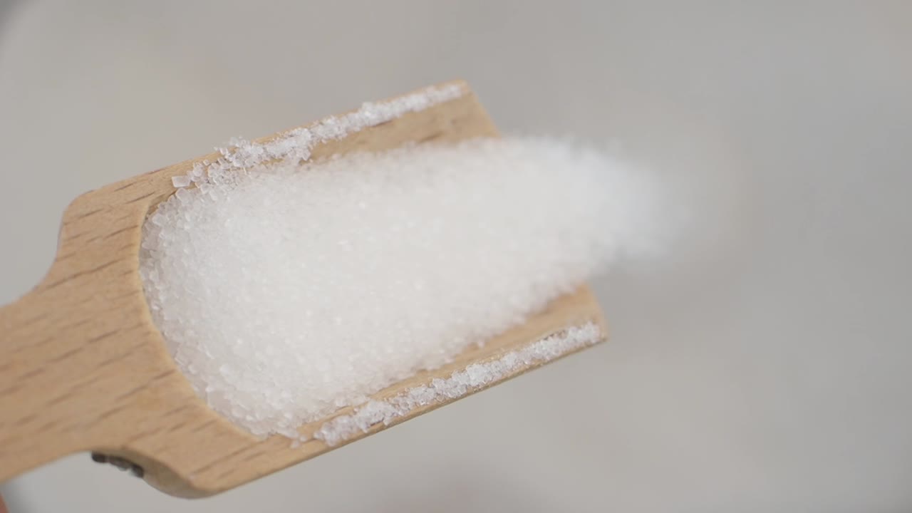 White granular substance in a wooden scoop