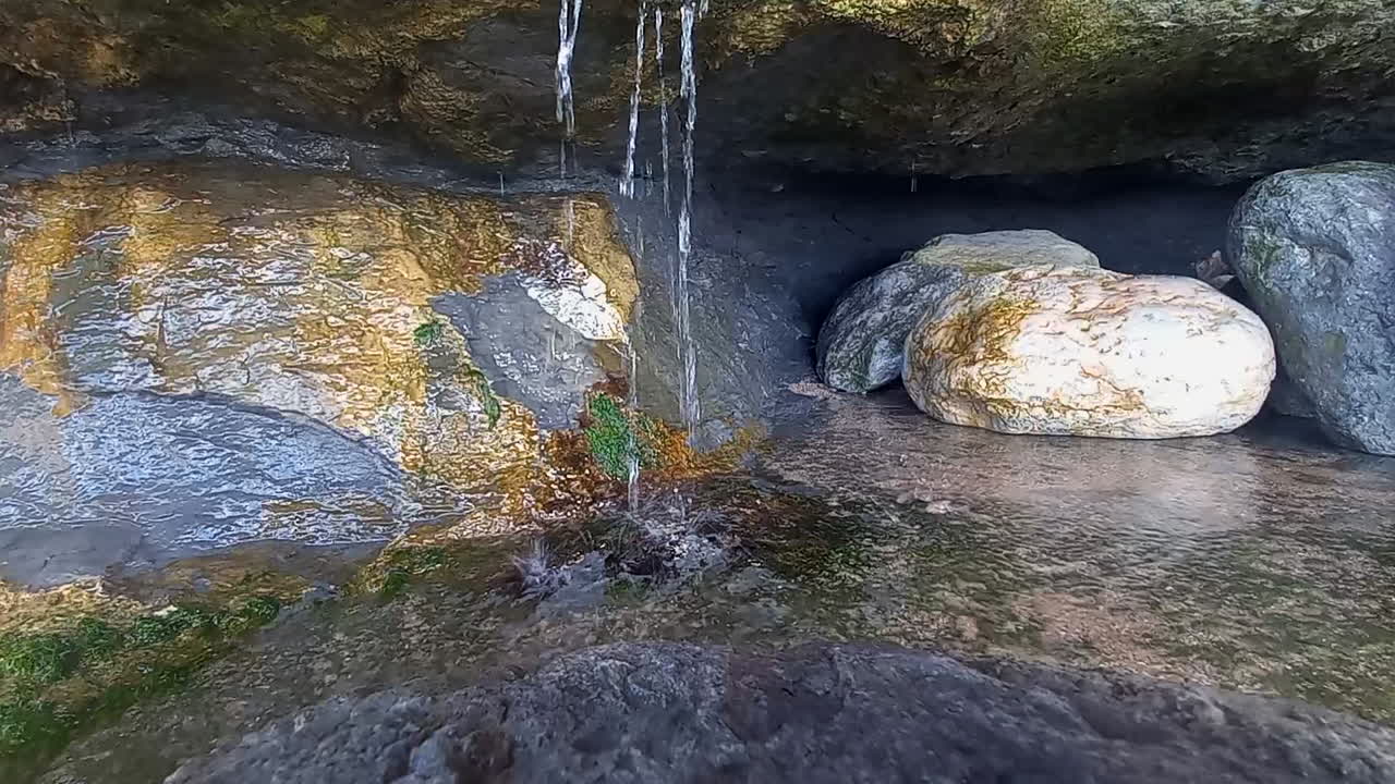 Clean water falling through the rocks of the caves on the hillside next to the sea
