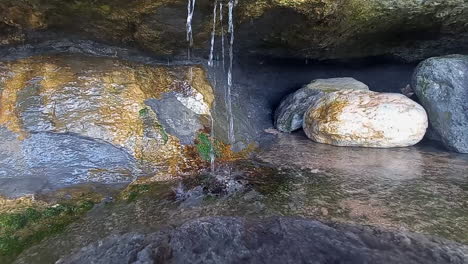 Agua-Limpia-Cayendo-A-Través-De-Las-Rocas-De-Las-Cuevas-En-La-Ladera-Junto-Al-Mar