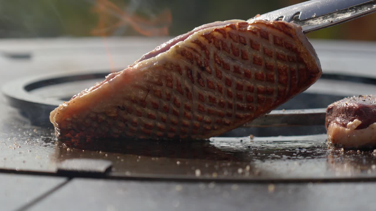 slowmotion shot of a chef checking the sear on the topside of a steak on a BBQ