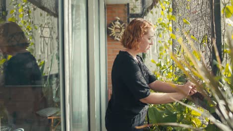 Profile view of caucasian woman removing dead leaves from her arbor with vines
