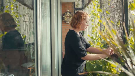 profile view of caucasian woman removing dead leaves from her arbor with vines