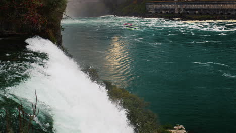 the flow of water of niagara falls, far away to the boat with tourists. evening before sunset