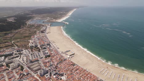 larga playa de arena blanca y ciudad turística de nazare, portugal