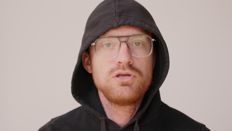 red haired man in a dirty hoodie making an awkward rap on a white backdrop