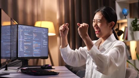 asian woman programmer celebrating succeed creating software engineer developing app, program, video game on desktop computer at home. terminal with coding language