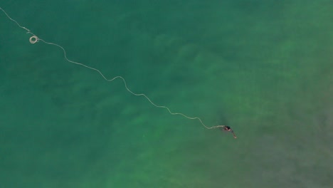 Aerial-top-down-view-of-fisherman-setting-the-trap-for-catching-fish-over-the-surface-of-water-in-ocean