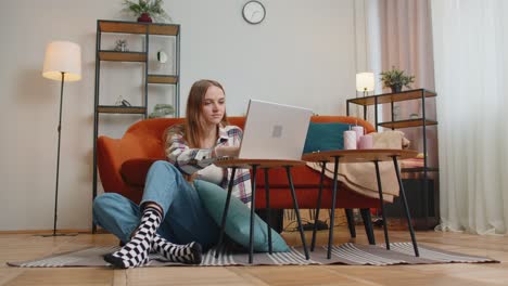 lovely young woman sitting on floor, using laptop pc share messages on social media application