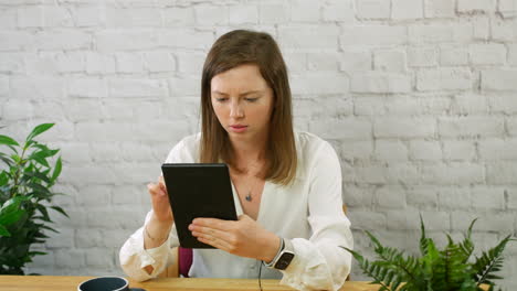 A-young-professional-business-woman-working-on-a-tablet-in-an-office-concentrating