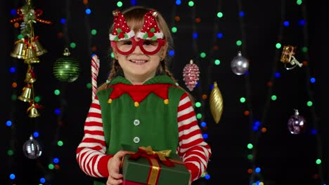 niña de navidad elfo santa ayudante dando caja de regalos de regalo a la cámara. feliz año nuevo vacaciones