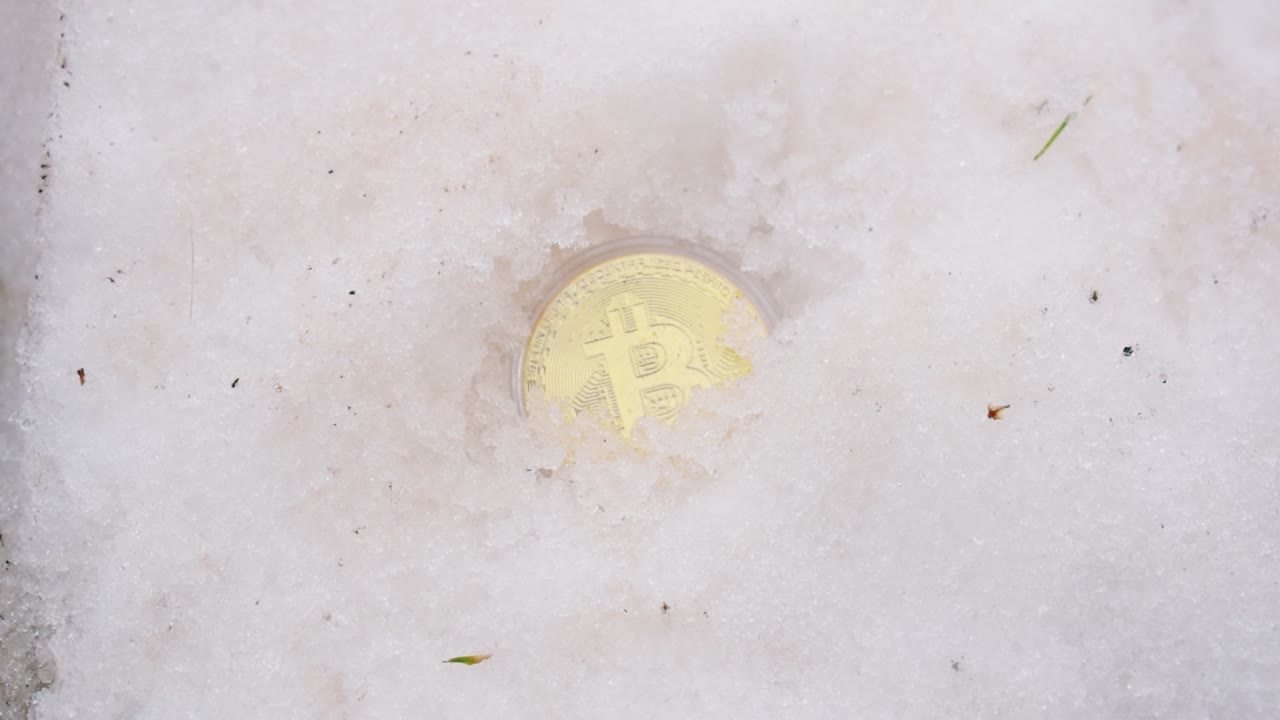 mano masculina excavando bitcoin dorado de la nieve
