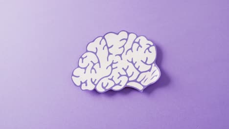 video of purple and white paper brain on purple background with copy space