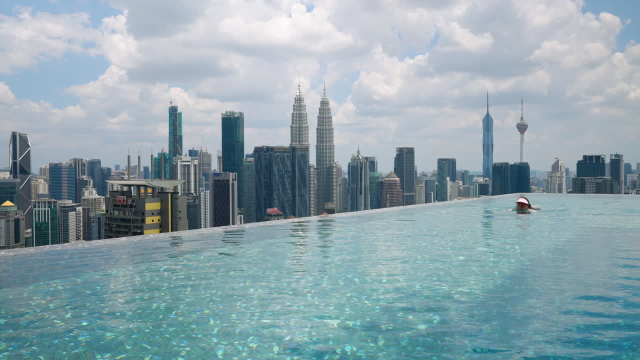 Mujer nadando en la piscina infinita de un hotel de lujo en la azotea en la ciudad de Kuala Lumpur, Malasia