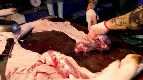 a butcher expertly trims fat from meat cuts.