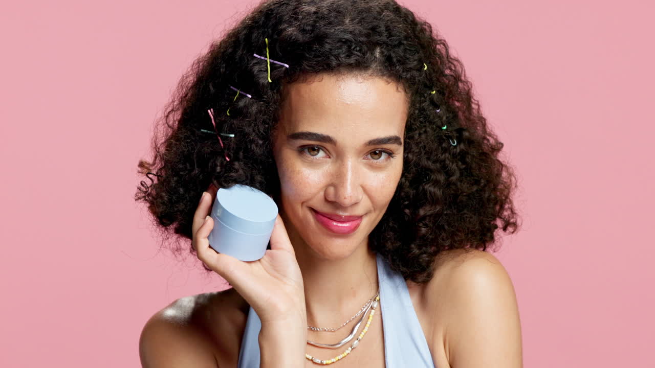 Woman with curly hair holding a skincare product
