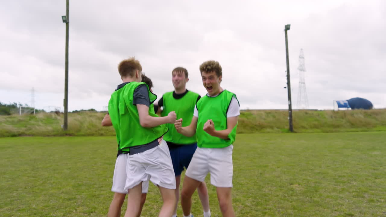 Male soccer players standing in row, observing game and celebrating on pitch