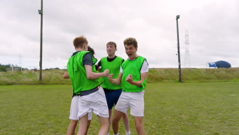 male soccer players standing in row, observing game and celebrating on pitch