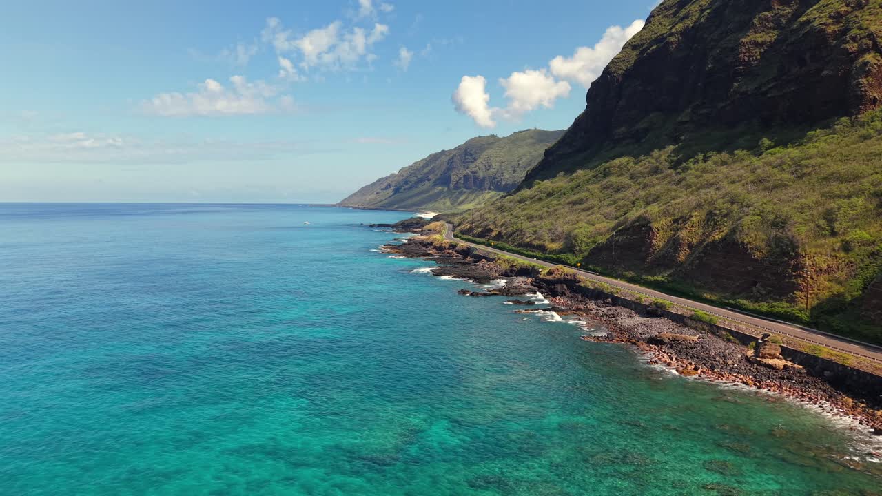 Autostrada costiera su una costa rocciosa con montagne ripide a Oahu, Hawaii, ripresa aerea.