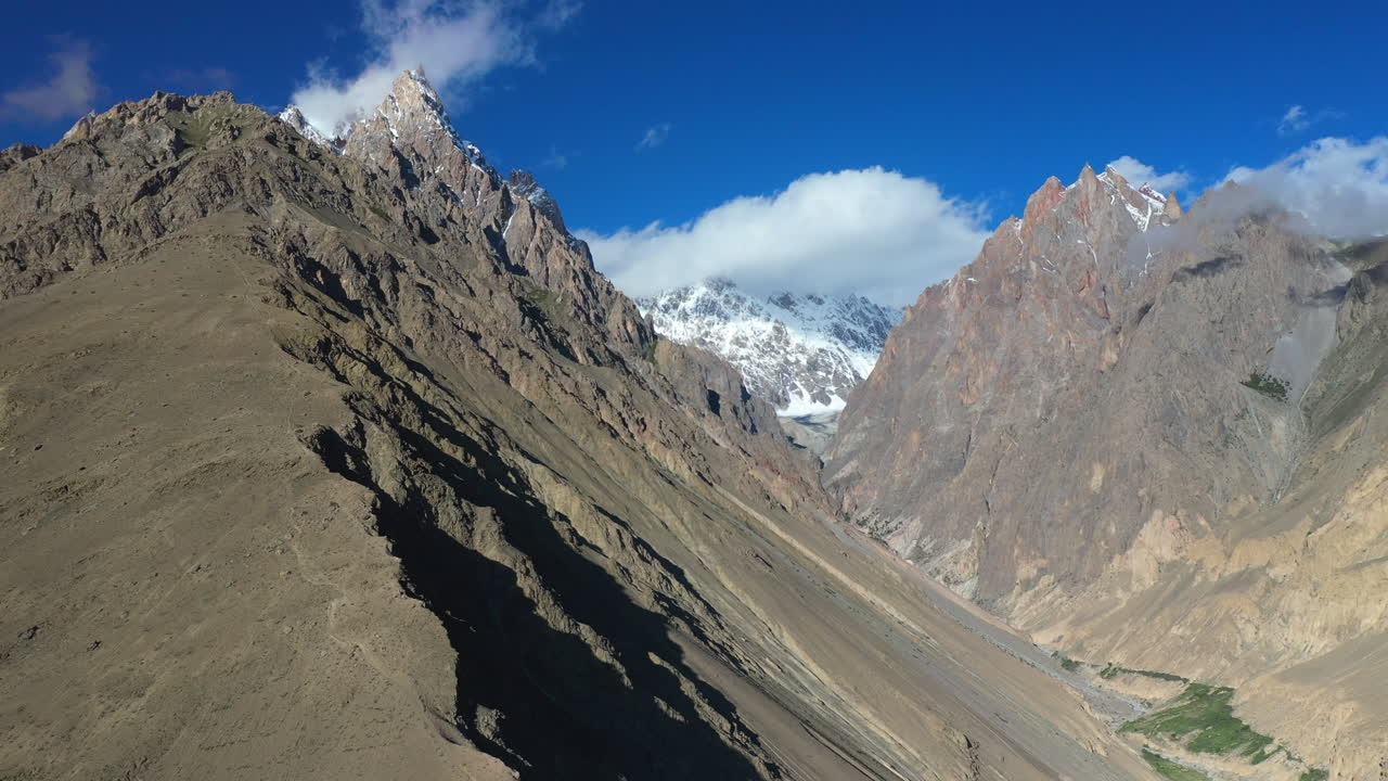 toma cinematográfica de drones del pico tupopdan, conos passu en hunza pakistán, picos montañosos cubiertos de nieve con acantilados escarpados, toma aérea alta y ancha-1