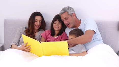 Familia-Leyendo-Un-Libro-De-Cuentos-En-La-Cama