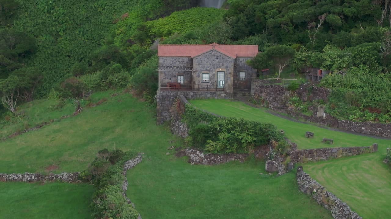 아조레스 의 강력 한 폭포 앞 에 있는 집 의 근접 촬영 - 드론 촬영