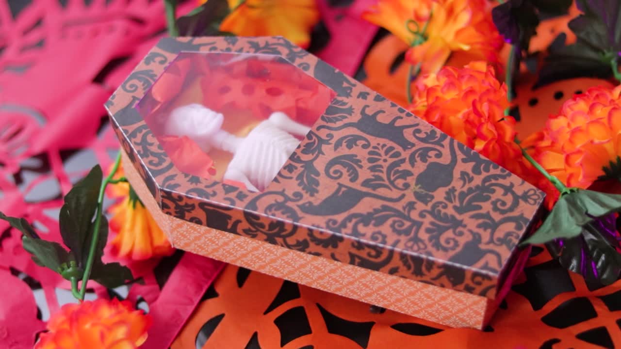Orange patterned box on a bed of vibrant Day of the Dead flowers, shallow focus