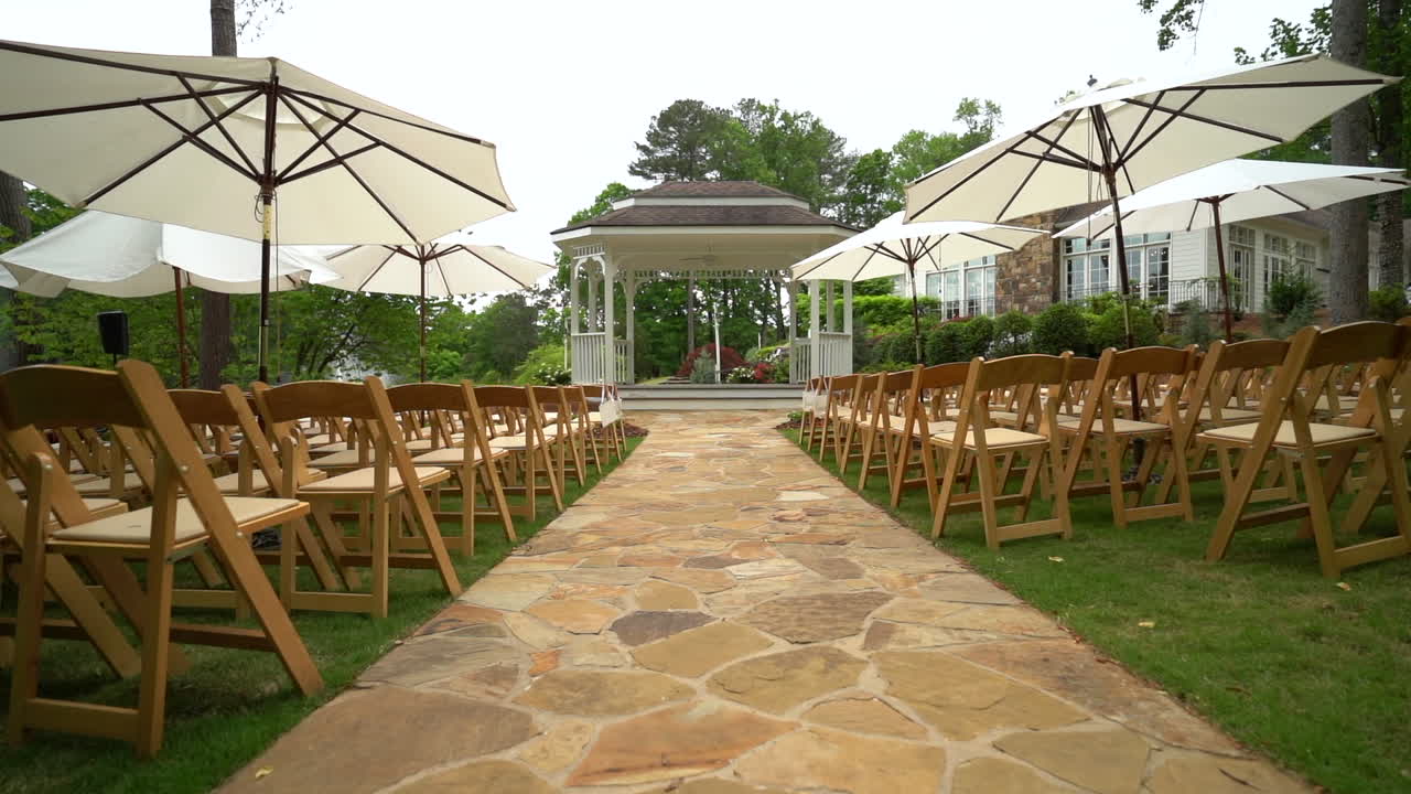 Beautiful outdoor wedding ceremony set up with wooden folding chairs by pond