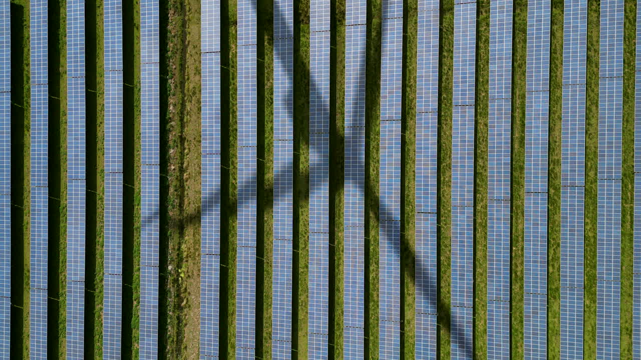 vista aérea de paneles solares con sombra de una turbina eólica giratoria-3