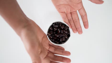 Top-down-view-of-coffee-beans-scattering-around-from-white-bowl-while-spinning